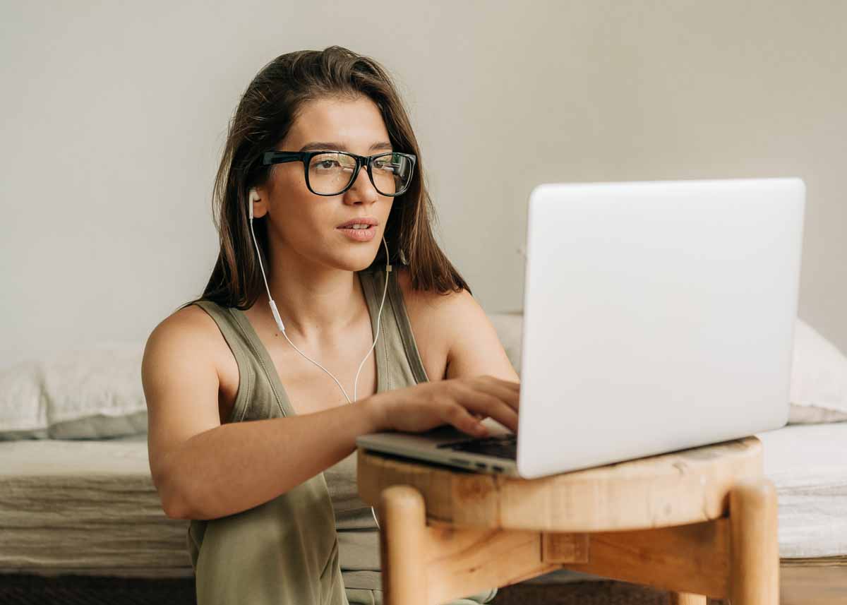 Jovem mulher estudando usando laptop e fones de ouvido