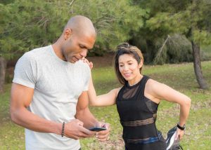 Mulher se alongando ao lado de homem musculoso, exemplo de personal trainer, nicho do mercado de trabalho para educação física